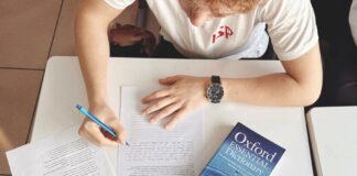 Jak skutecznie uczyć się słówek: praktyczne strategie dla uczących się języków obcych Student pisze test przy biurku z papierem i słownikiem Oxford