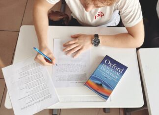 Jak skutecznie uczyć się słówek: praktyczne strategie dla uczących się języków obcych Student pisze test przy biurku z papierem i słownikiem Oxford