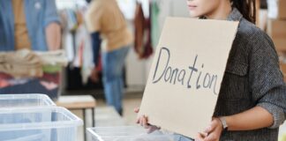Jak zorganizować lokalną zbiórkę dla WOŚP w Tarnobrzegu: praktyczny przewodnik dla wolontariuszy i mieszkańców Wolontariusz trzyma karton z napisem donation przy puszkach na datki