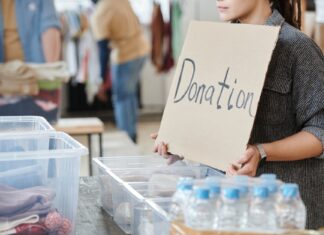 Wolontariusz trzyma karton z napisem donation przy puszkach na datki